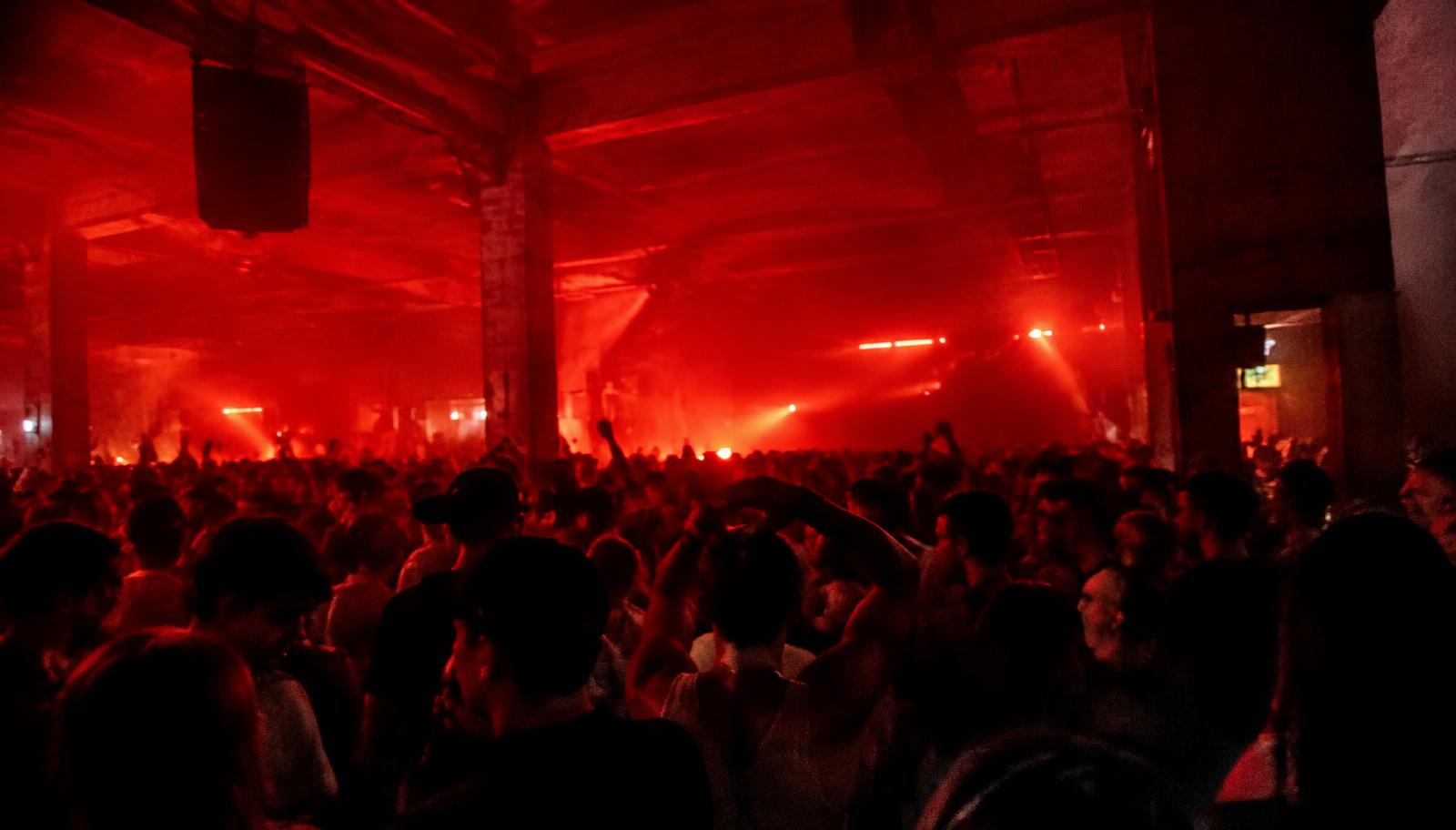 Público en un evento de música electrónica con luz roja